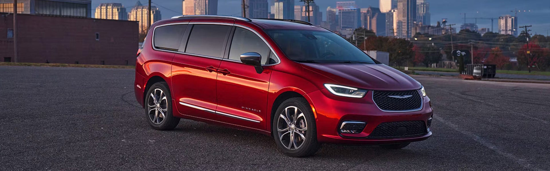 Red Chrysler Pacifica parked with a city skyline in the background